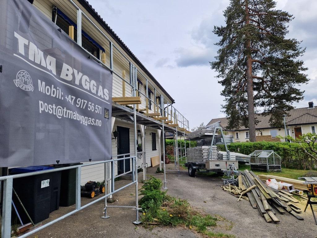 TMA Bygg-banneret med telefonnummer og e-post, hengt på stillaset ved en jobb